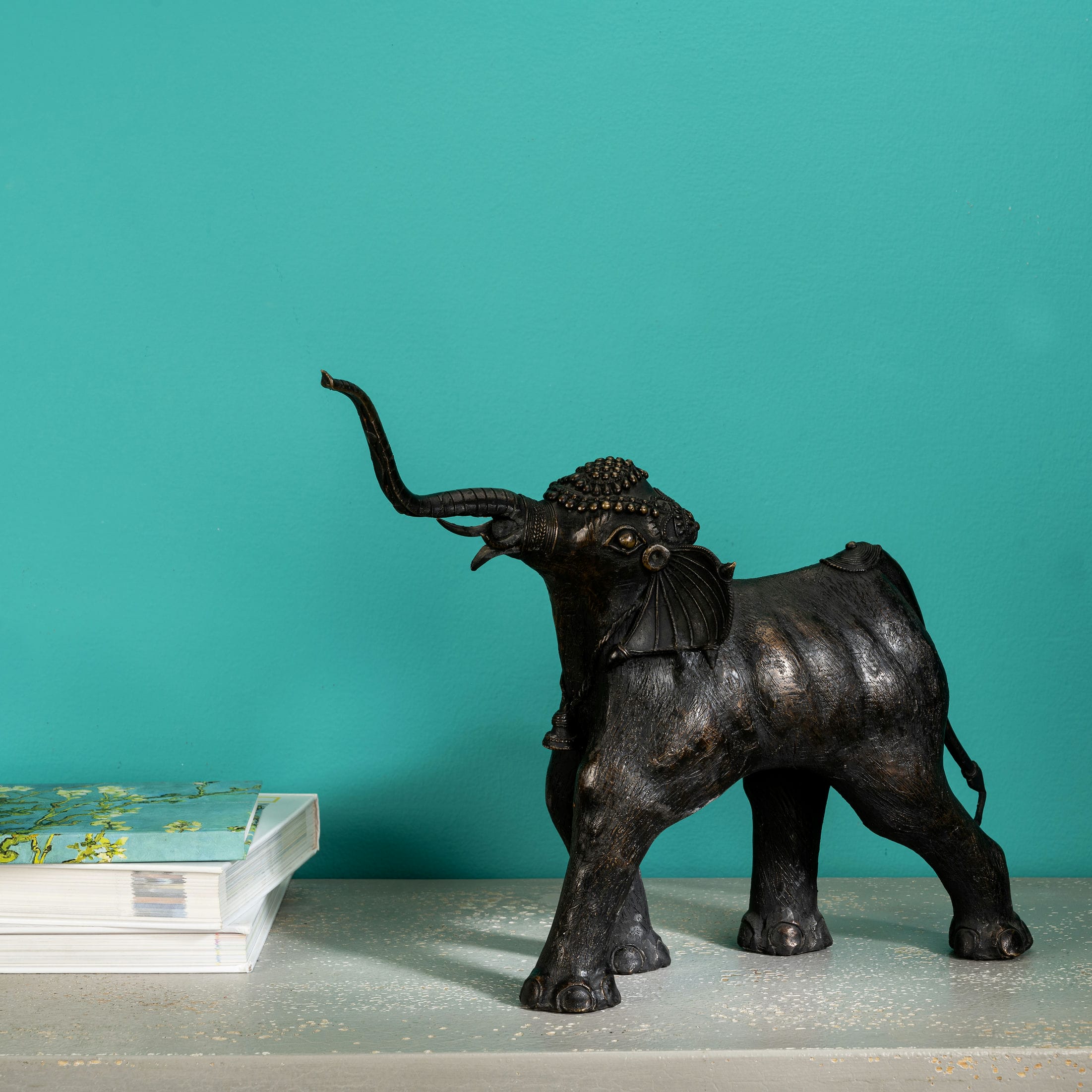 Handcrafted heavy metal animal idol wearing a traditional bell necklace for a living room credenza or cultural showcase.