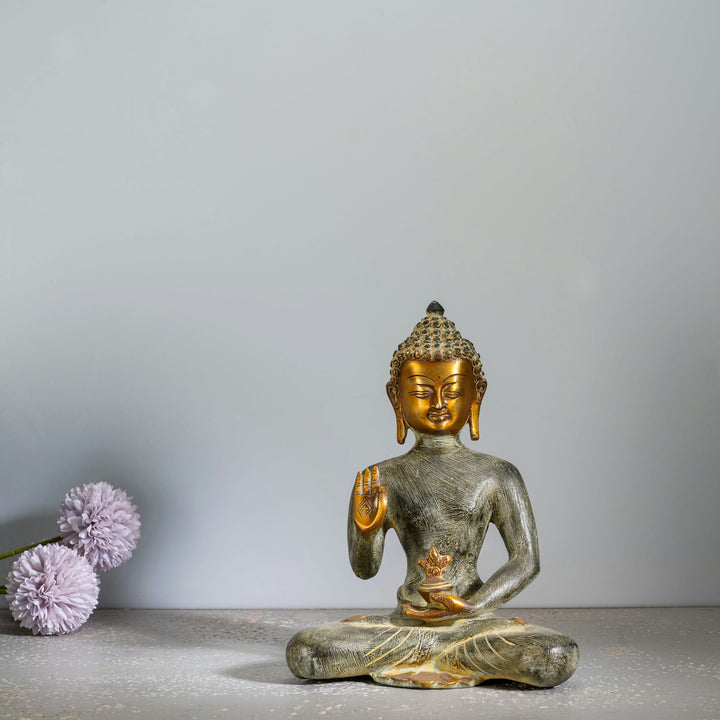 Etched Brass Abhaya Buddha Statue resting in the Padmasana posture on a low natural-edge wooden altar. 
