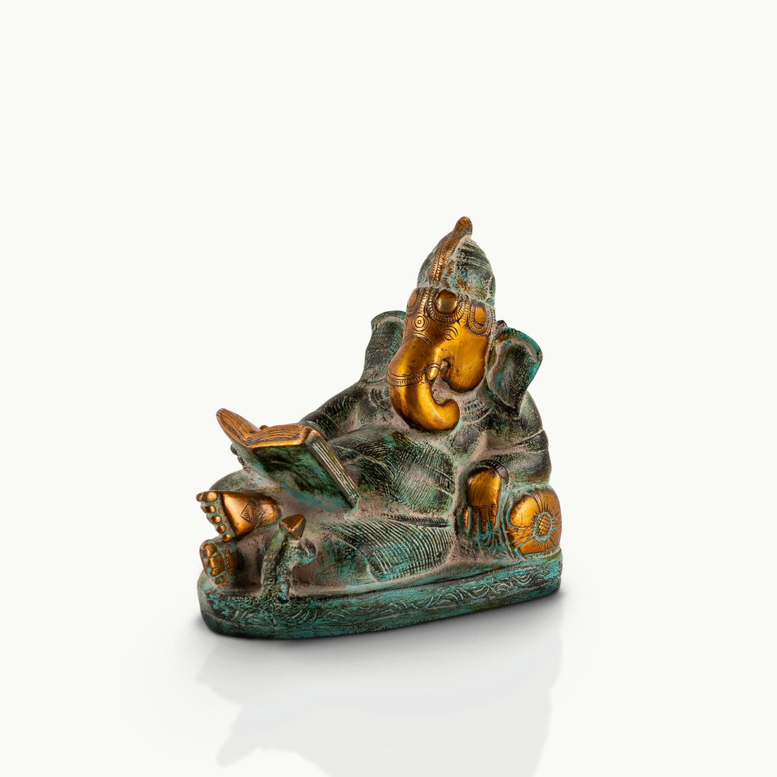 Reading Ganesha Brass Statue reclining gracefully against a pillow on an executive desk. 