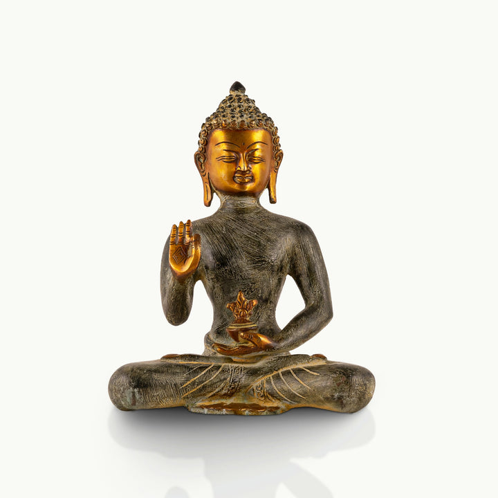 Etched Brass Abhaya Buddha Statue resting in the Padmasana posture on a low natural-edge wooden altar. 