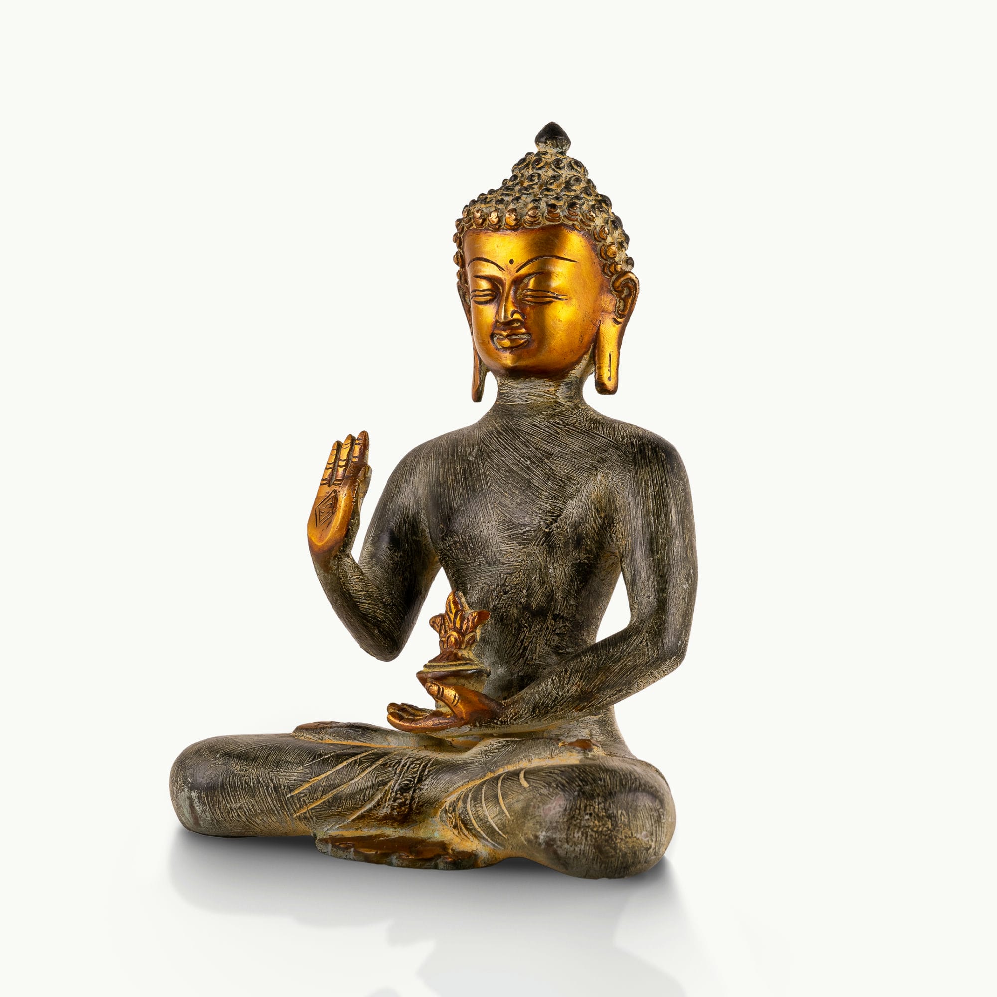Etched Brass Abhaya Buddha Statue resting in the Padmasana posture on a low natural-edge wooden altar. 