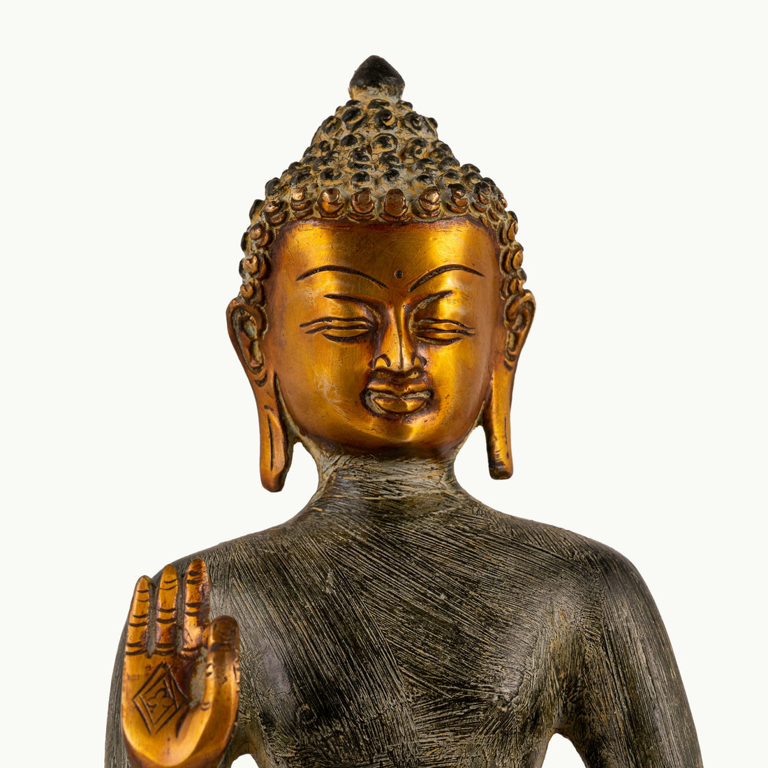 Etched Brass Abhaya Buddha Statue resting in the Padmasana posture on a low natural-edge wooden altar. 