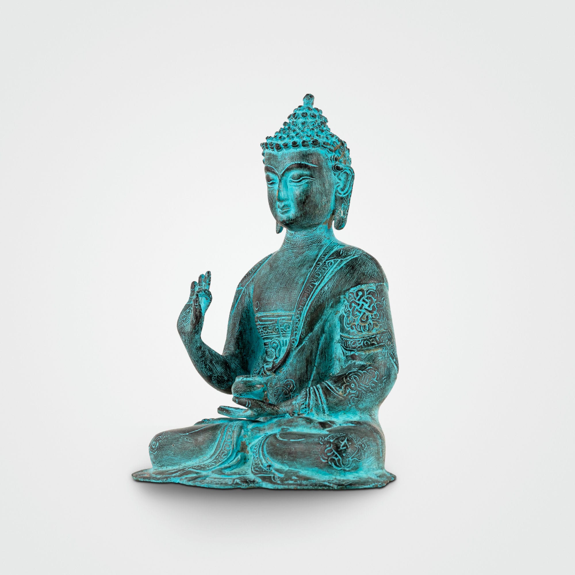 Hand-engraved Tibetan meditation idol with a striking teal patina for a living room mantle or Vastu alignment.
