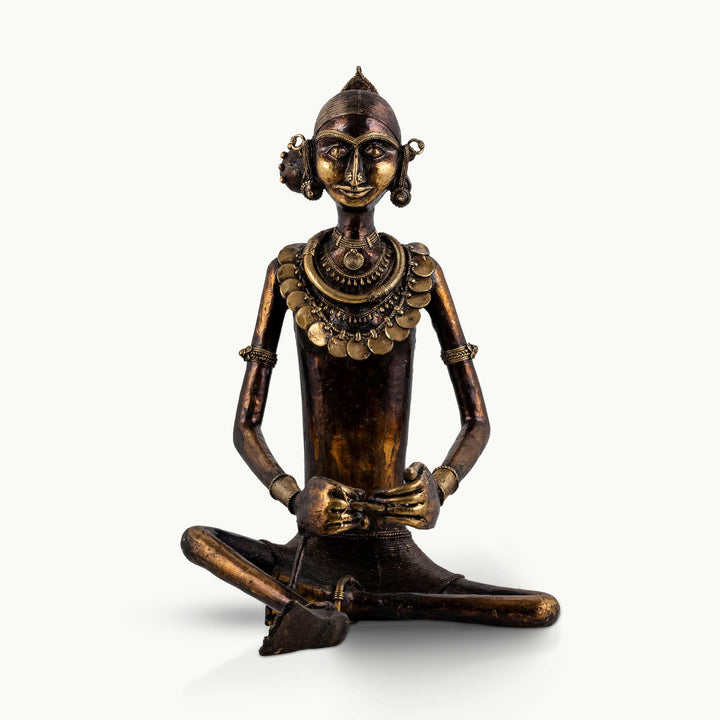 Tribal brass woman sculpture at a traditional grinding stone with an antiqued finish.