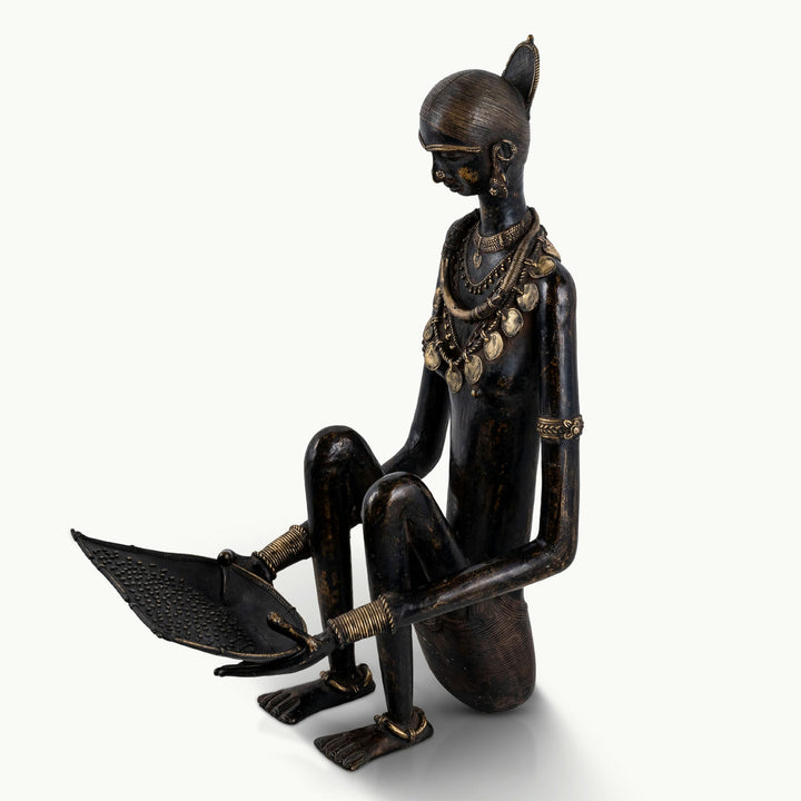 Black brass tribal figure winnowing grain with a dual-tone finish.
