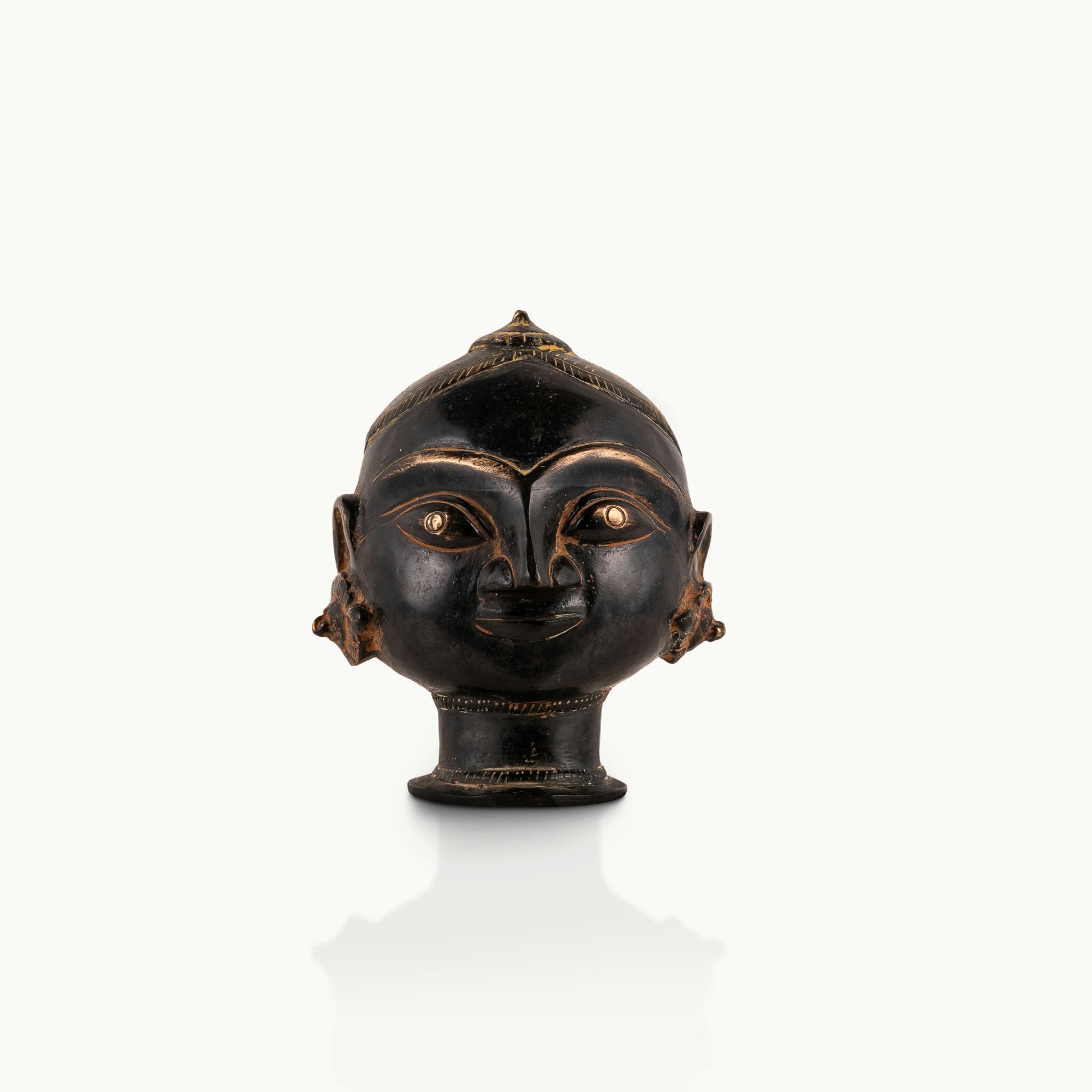 Black Brass Tribal Head Sculpture projecting an ancestral presence on a floating gallery shelf. 