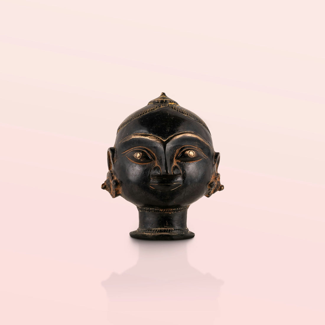 Black Brass Tribal Head Sculpture projecting an ancestral presence on a floating gallery shelf. 