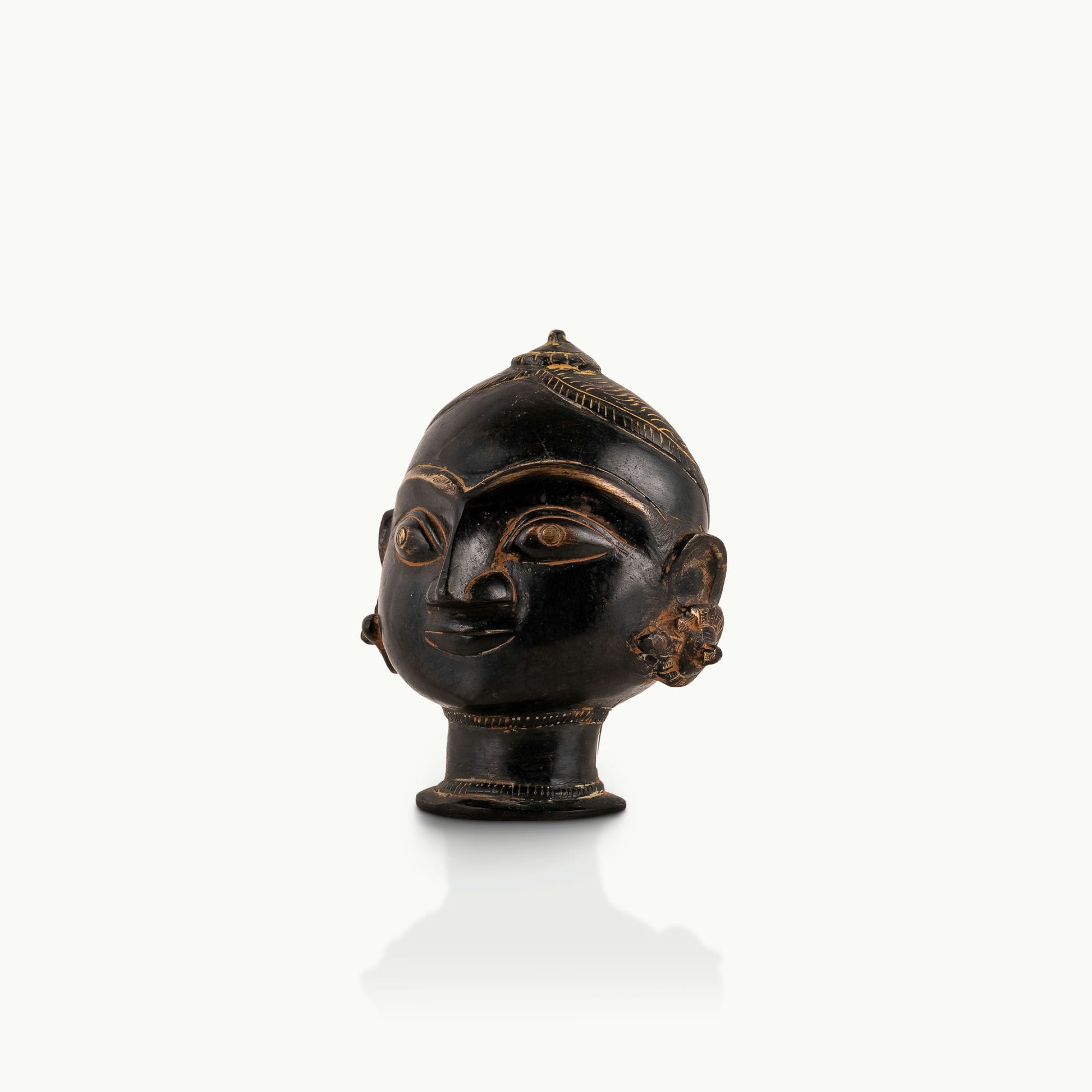 Black Brass Tribal Head Sculpture projecting an ancestral presence on a floating gallery shelf. 