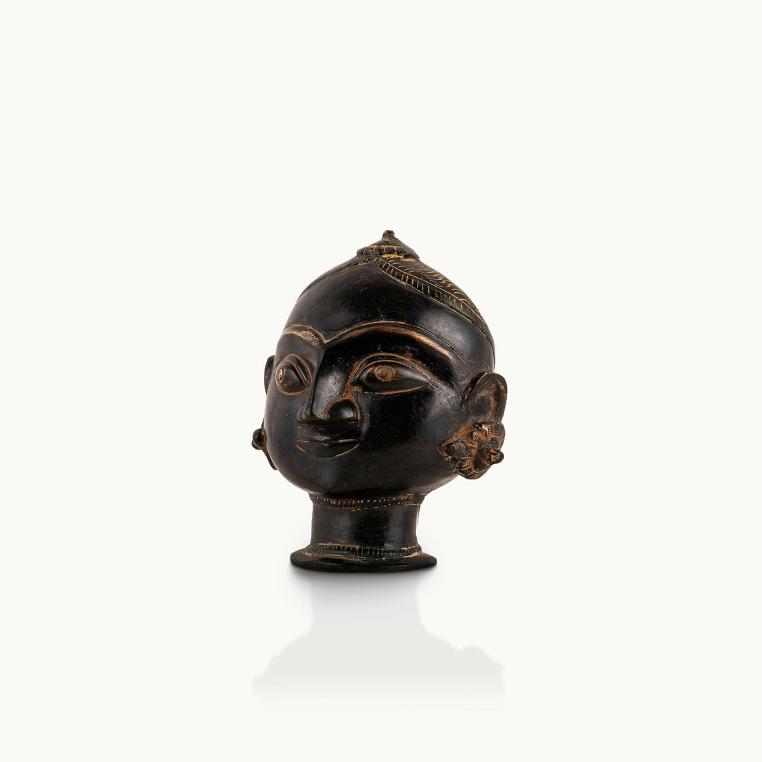 Black Brass Tribal Head Sculpture projecting an ancestral presence on a floating gallery shelf. 