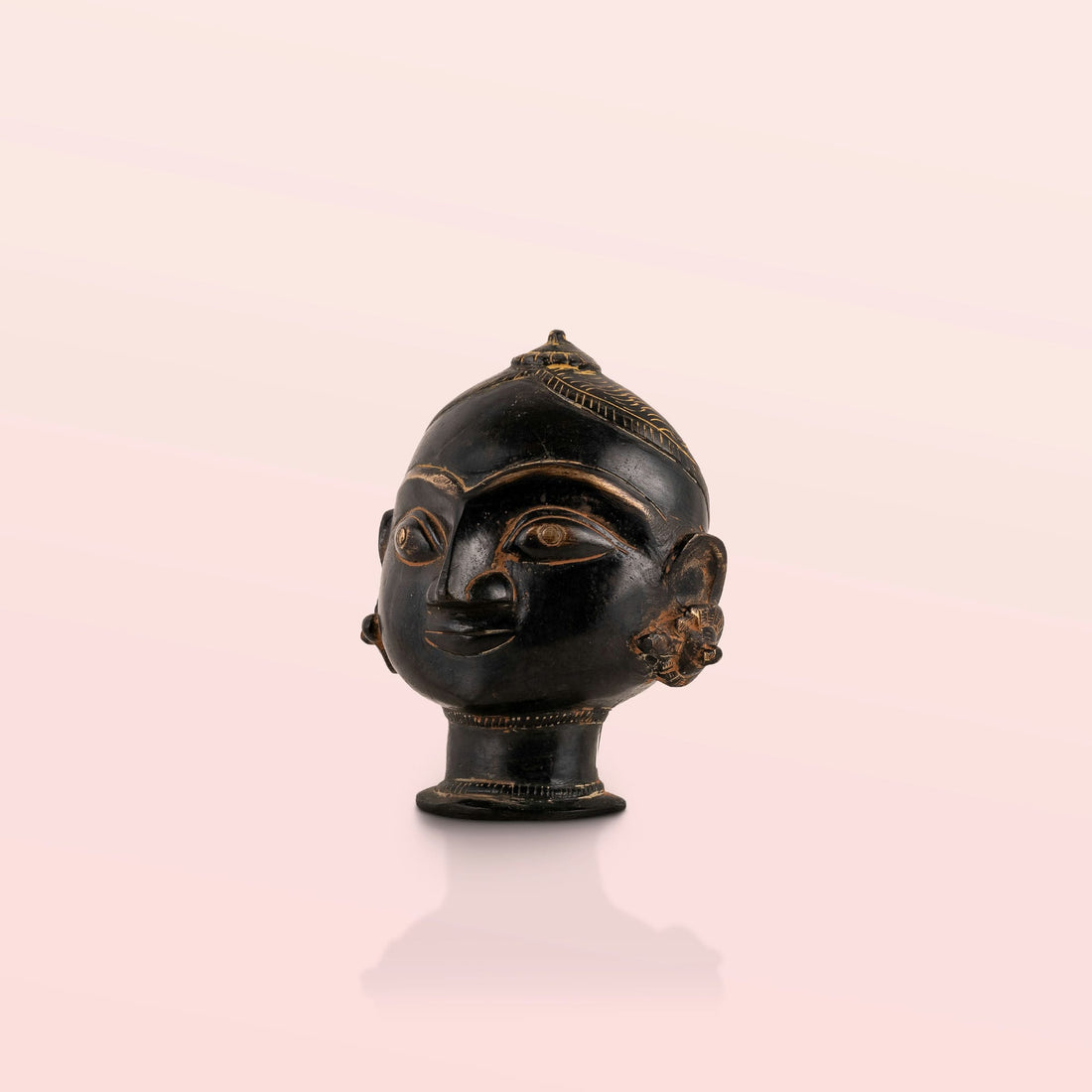 Black Brass Tribal Head Sculpture projecting an ancestral presence on a floating gallery shelf. 