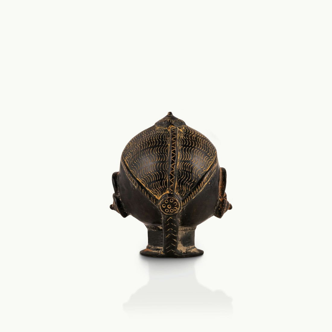 Black Brass Tribal Head Sculpture projecting an ancestral presence on a floating gallery shelf. 
