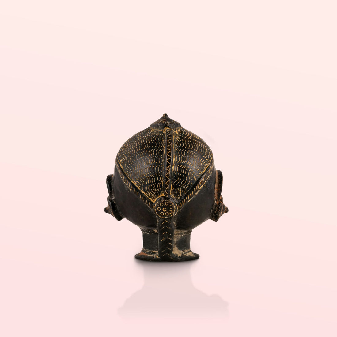 Black Brass Tribal Head Sculpture projecting an ancestral presence on a floating gallery shelf. 