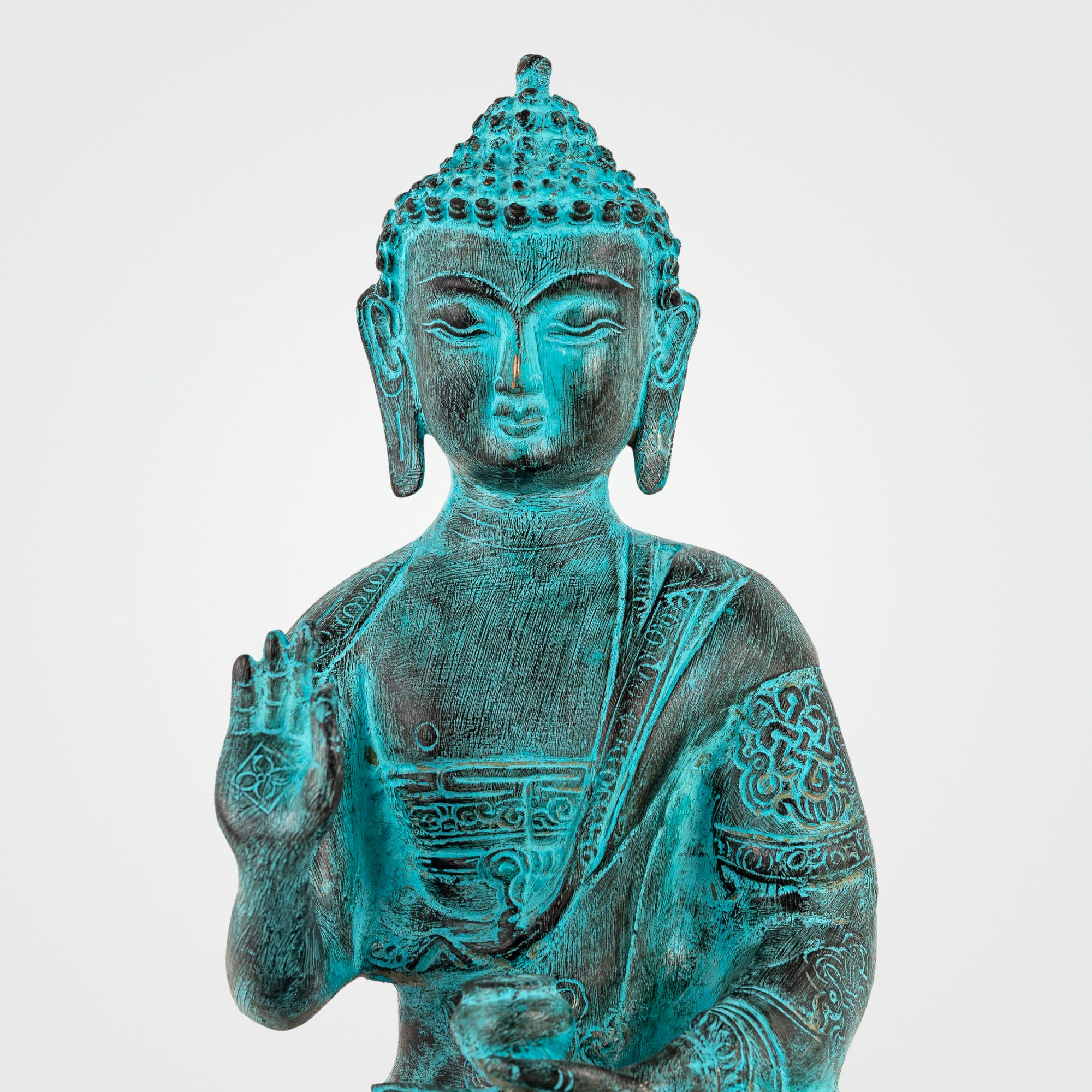 Hand-engraved Tibetan meditation idol with a striking teal patina for a living room mantle or Vastu alignment.