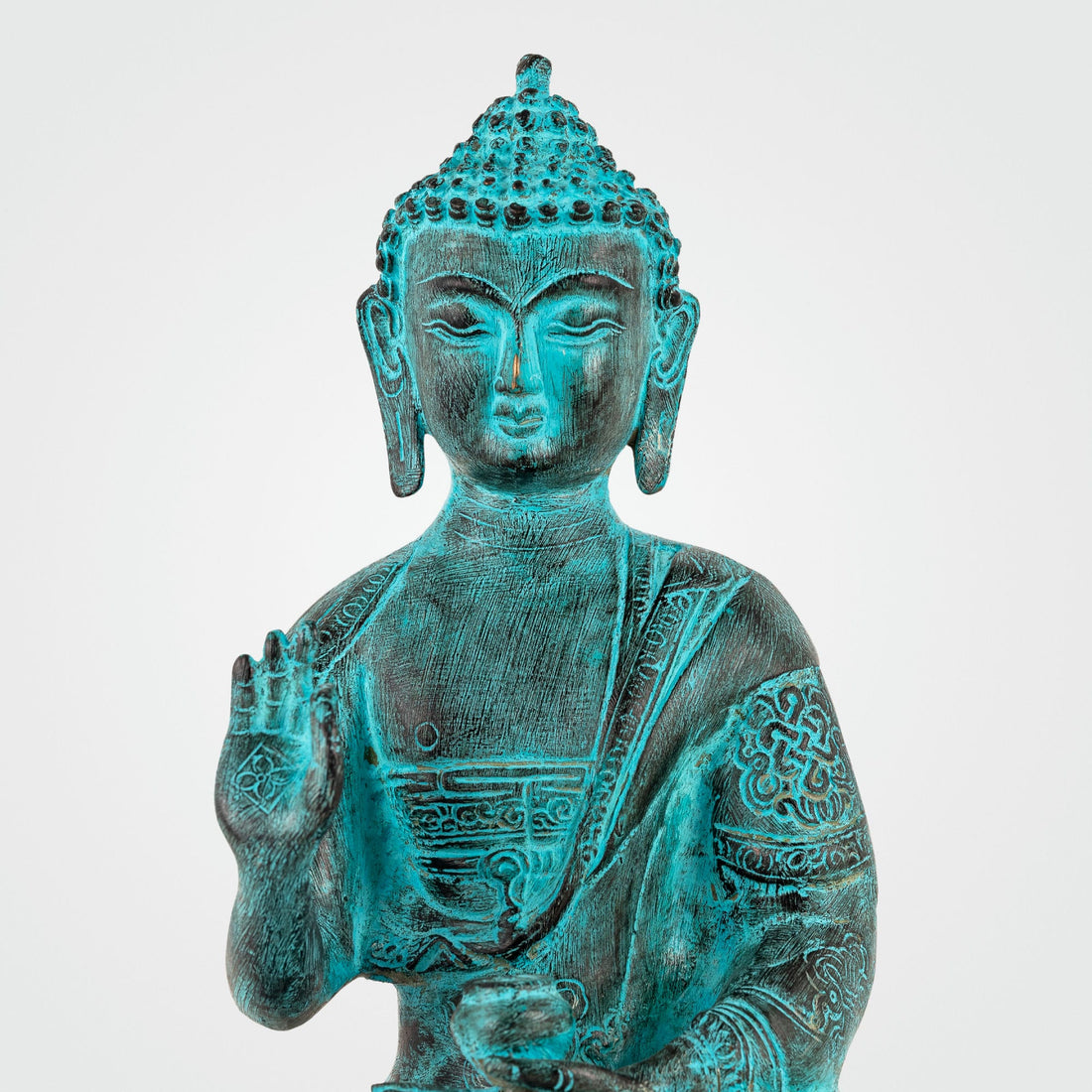 Hand-engraved Tibetan meditation idol with a striking teal patina for a living room mantle or Vastu alignment.