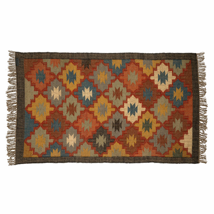 Handwoven checkered wool jute dhurrie in a dining room, with a rust and slate blue diamond mosaic. 