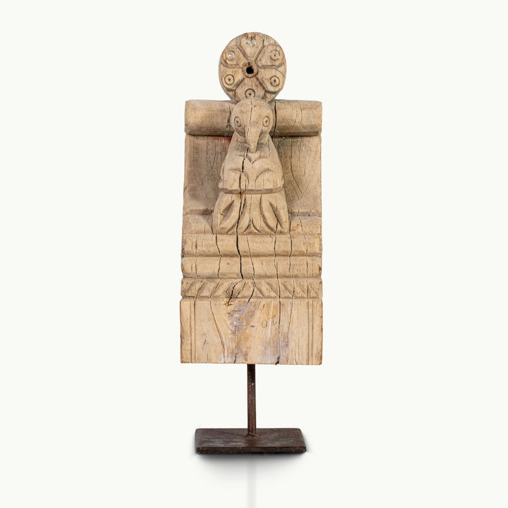 Bleached wooden haveli corbel featuring a carved avian figure and rosette.