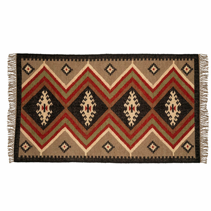 Central diamond wool jute dhurrie in a living room, with radiating earthy rust and taupe geometric bands. 