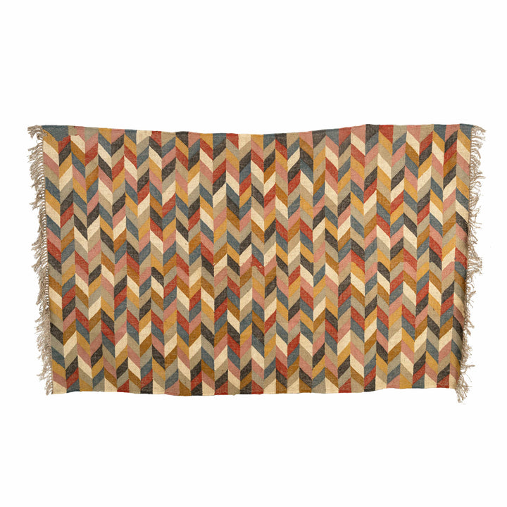 Herringbone wool jute dhurrie in a hallway, weaving rust red, yellow, and blue interlocking chevrons. 