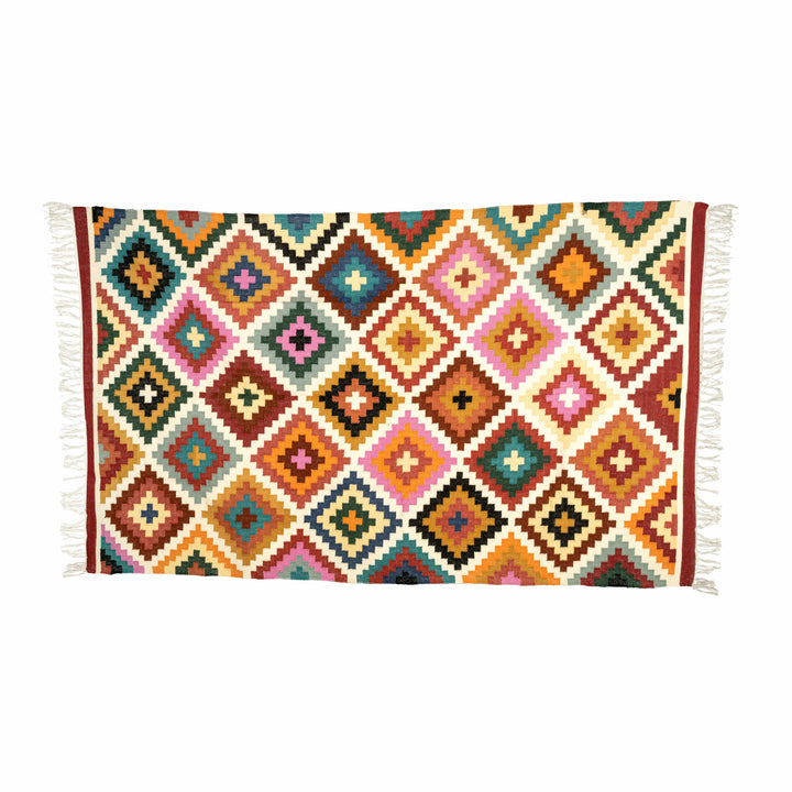 Multicolour diamond cotton wool dhurrie in a living room, with pixelated teal and blush pink diamonds. 
