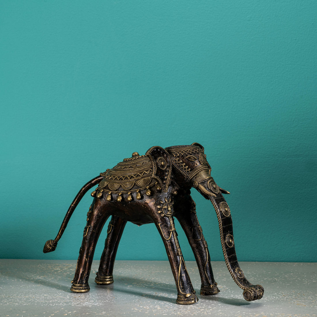 Indian metal ceremonial beast decor featuring a stylized elongated trunk for a wide wooden bookshelf or traditional home decor.