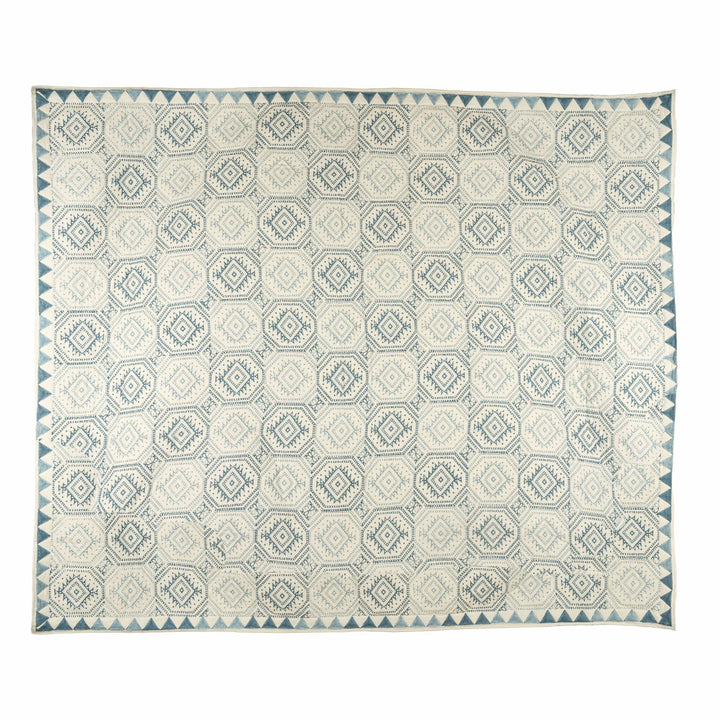 Indigo block-print cotton bedcover with a continuous hexagon lattice, stepped diamonds, and a sawtooth triangle border.