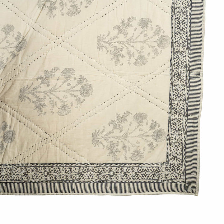 Monochrome block-print cotton bedcover featuring charcoal lotus motifs inside large diamond-quilted channel stitching.