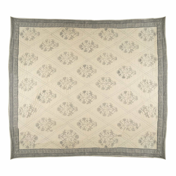 Monochrome block-print cotton bedcover featuring charcoal lotus motifs inside large diamond-quilted channel stitching.