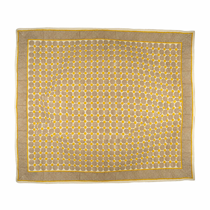 Mustard block-print cotton bedcover folded, showcasing taupe spheres and golden polka dots for a master bedroom setup.