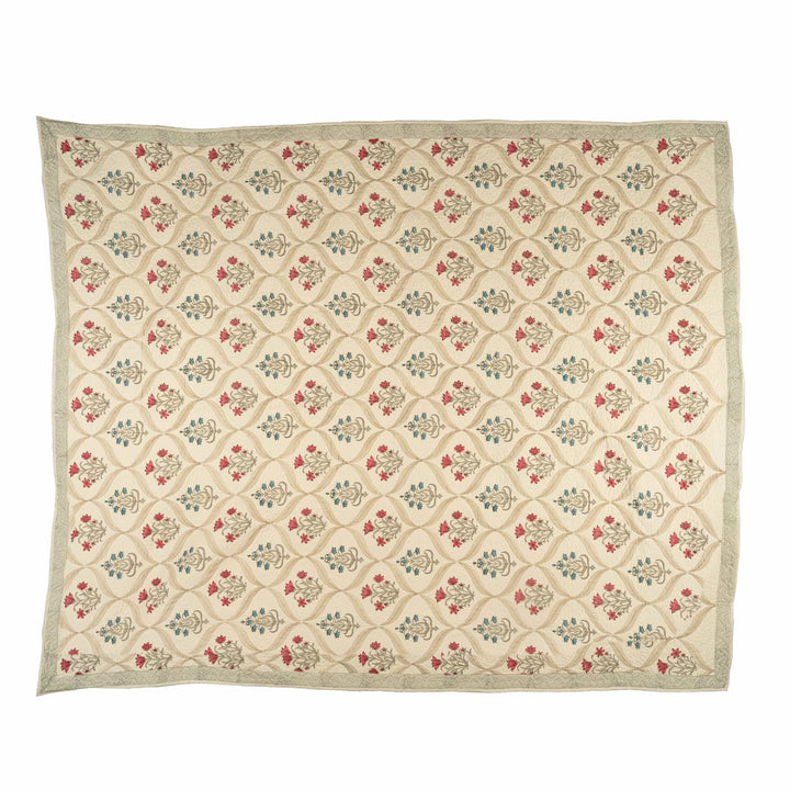 Floral ogee block-print cotton bedcover folded, showcasing bright pink and powder-blue botanical sprigs for a master suite.