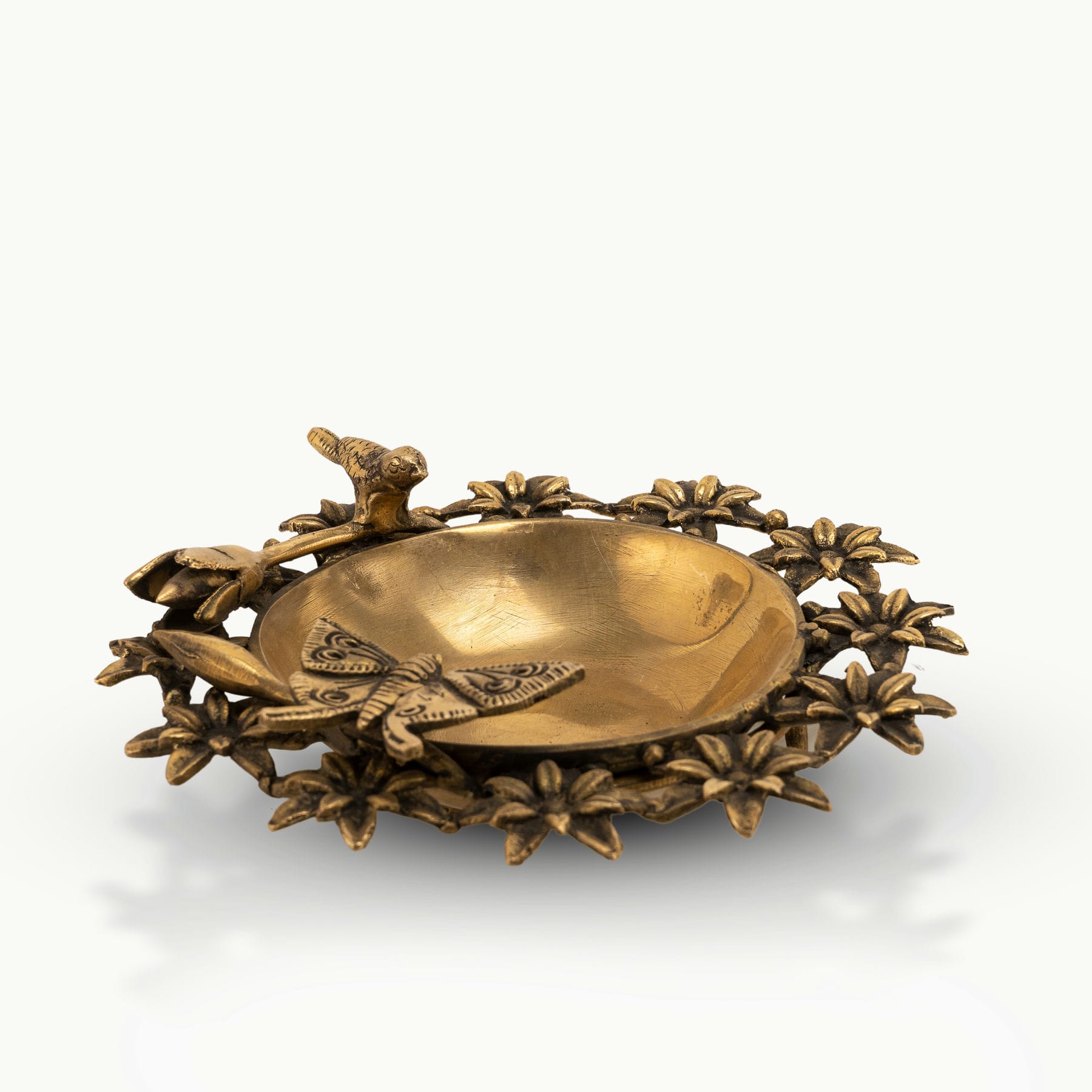 Antique Brass Floral Decorative Bowl framed by sculpted wildlife on an entryway table. 