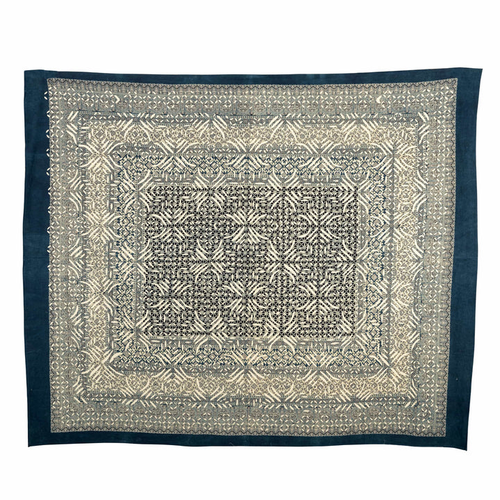 Indigo appliqué cotton bedcover draped in a contemporary master suite featuring high-contrast geometric starburst cut-outs.