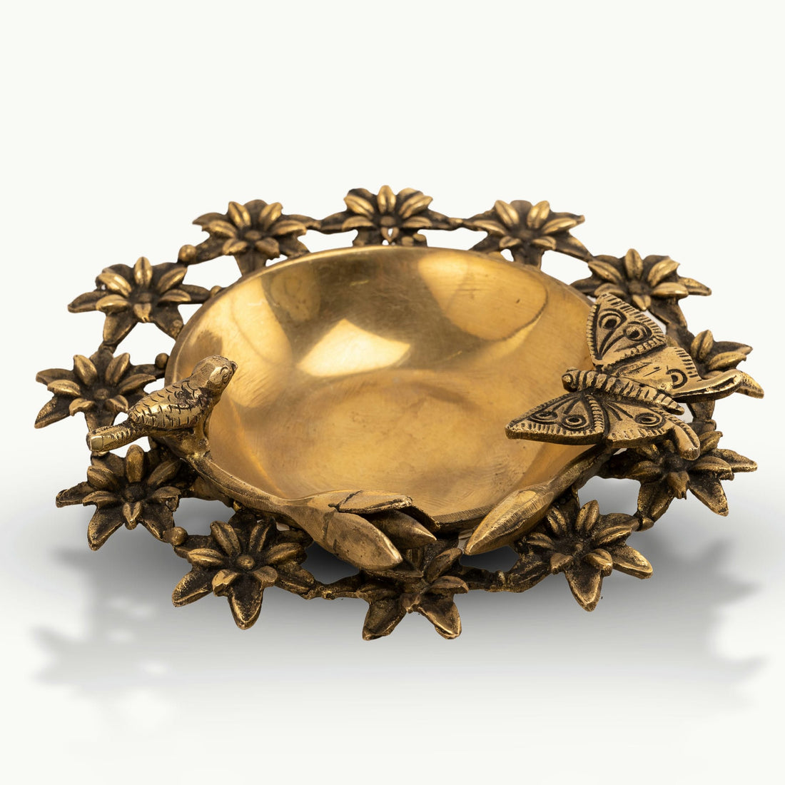 Antique Brass Floral Decorative Bowl framed by sculpted wildlife on an entryway table. 