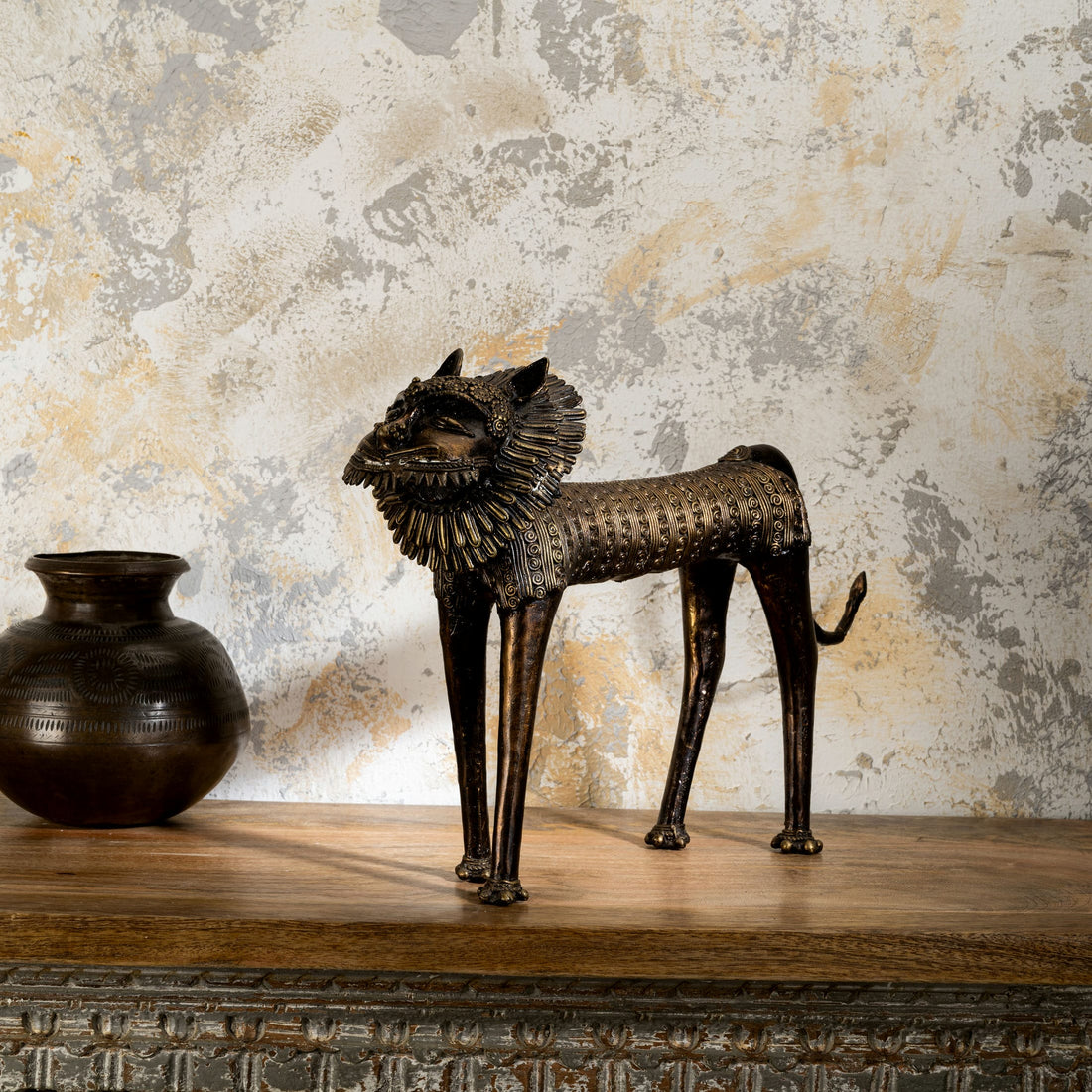 Dhokra style bronze feline featuring a wire-like mane and tribal geometry for a wide mantelpiece or rustic home styling.