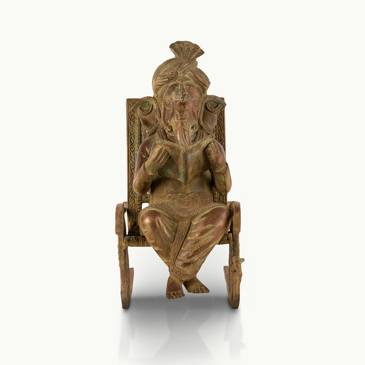 Antique Brass Rocking Chair Ganesha engrossed in a manuscript for a mahogany desk.