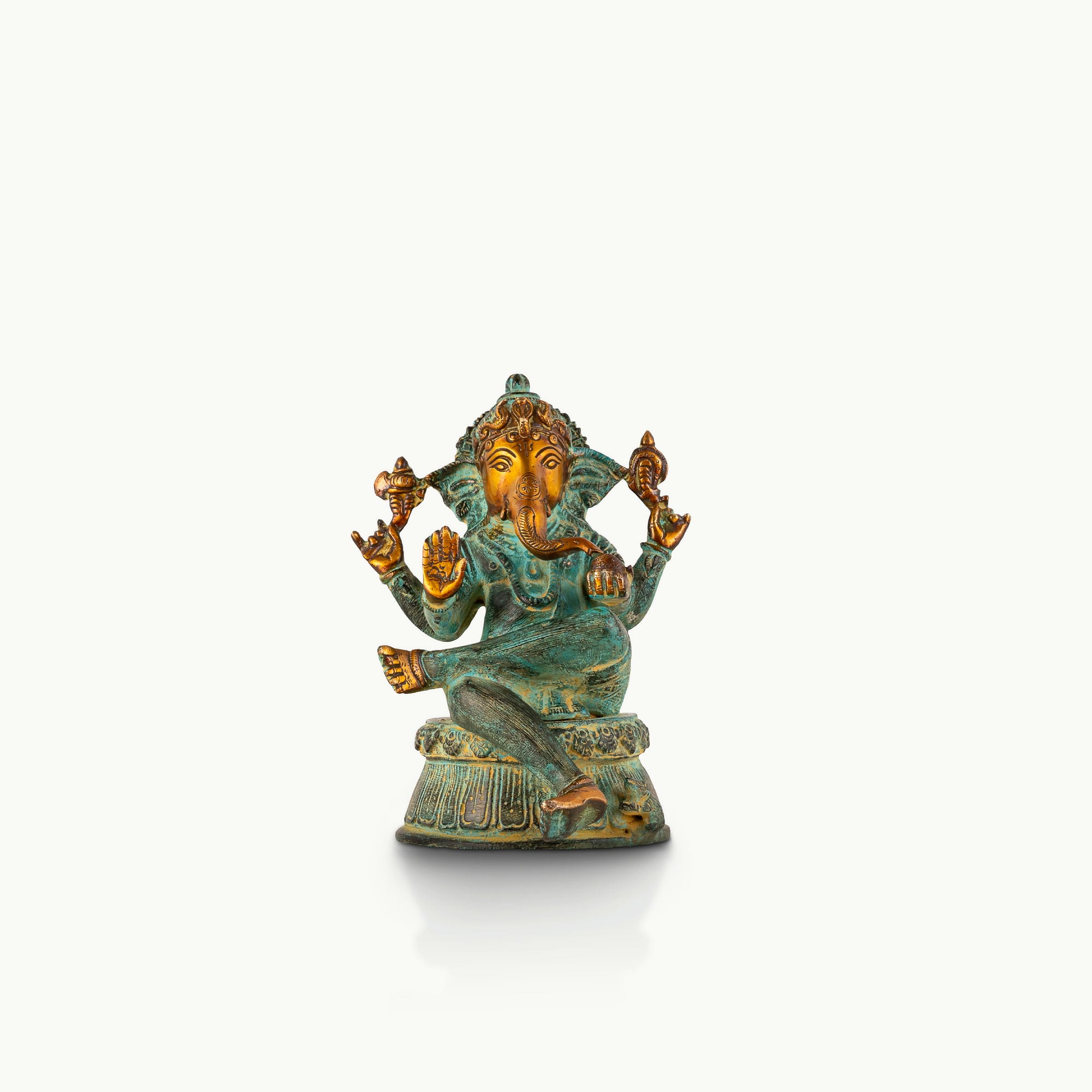 Verdigris Brass Seated Ganesha in a relaxed Lalitasana for a light-wood console.