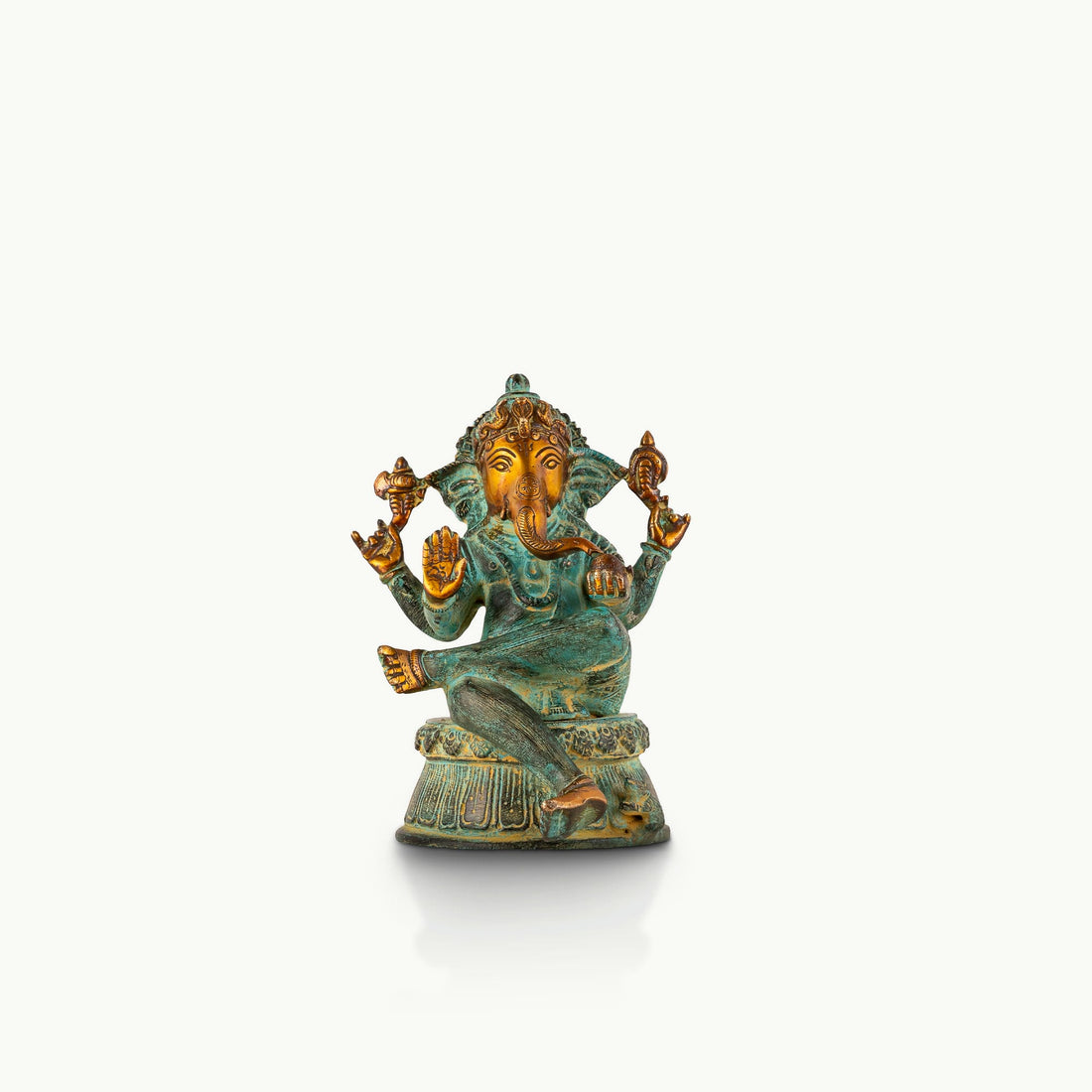 Verdigris Brass Seated Ganesha in a relaxed Lalitasana for a light-wood console.