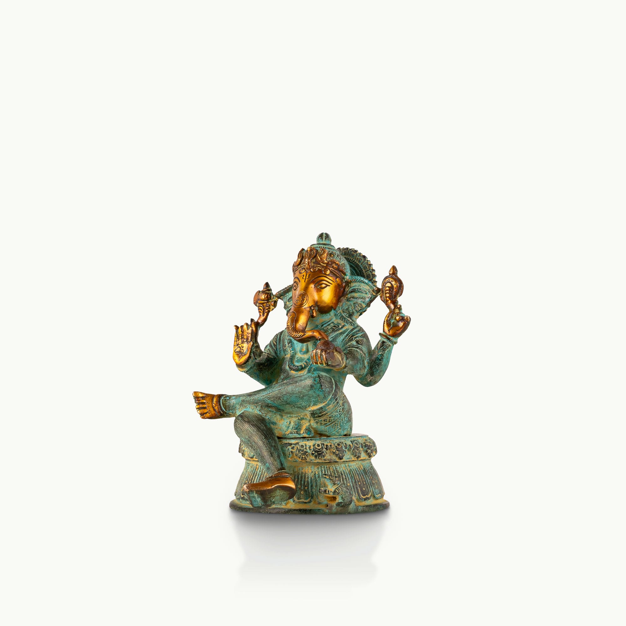 Verdigris Brass Seated Ganesha in a relaxed Lalitasana for a light-wood console.