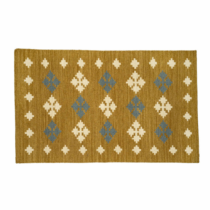 Flatweave cotton wool area rug in a bedroom, featuring stepped geometric crosses on a mustard canvas. 