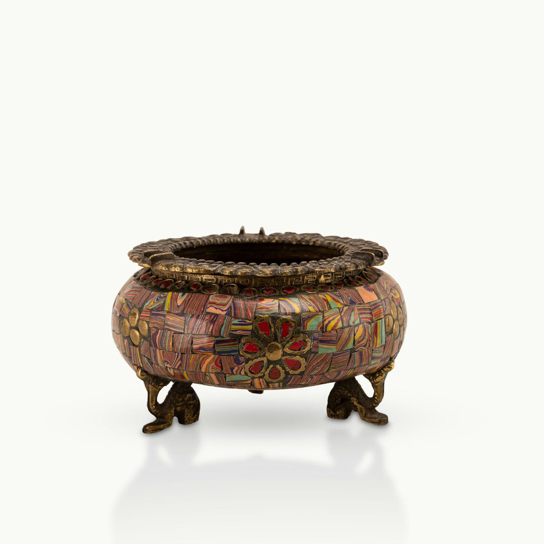 Brass Elephant Foot Mosaic Ashtray decorated with vibrant stones on a dark wood coffee table. 