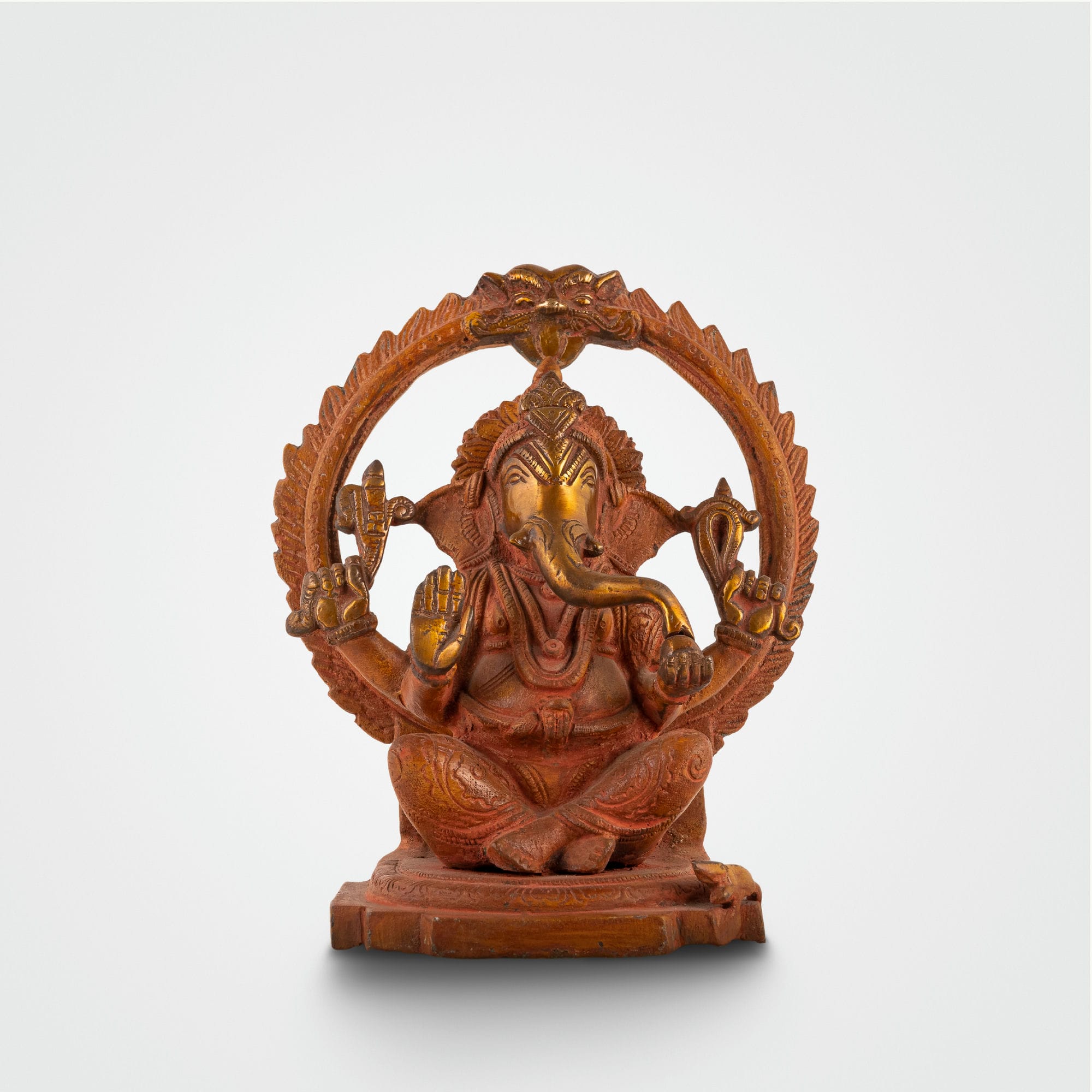 Red Oxidised Brass Ganesha Statue framed by a swirling halo on a home altar. 