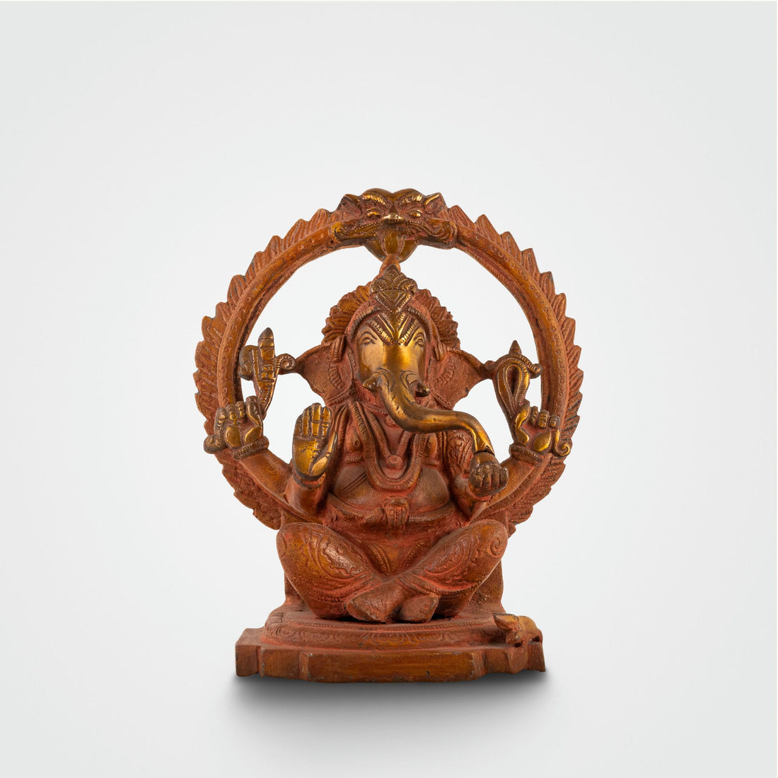 Red Oxidised Brass Ganesha Statue framed by a swirling halo on a home altar. 