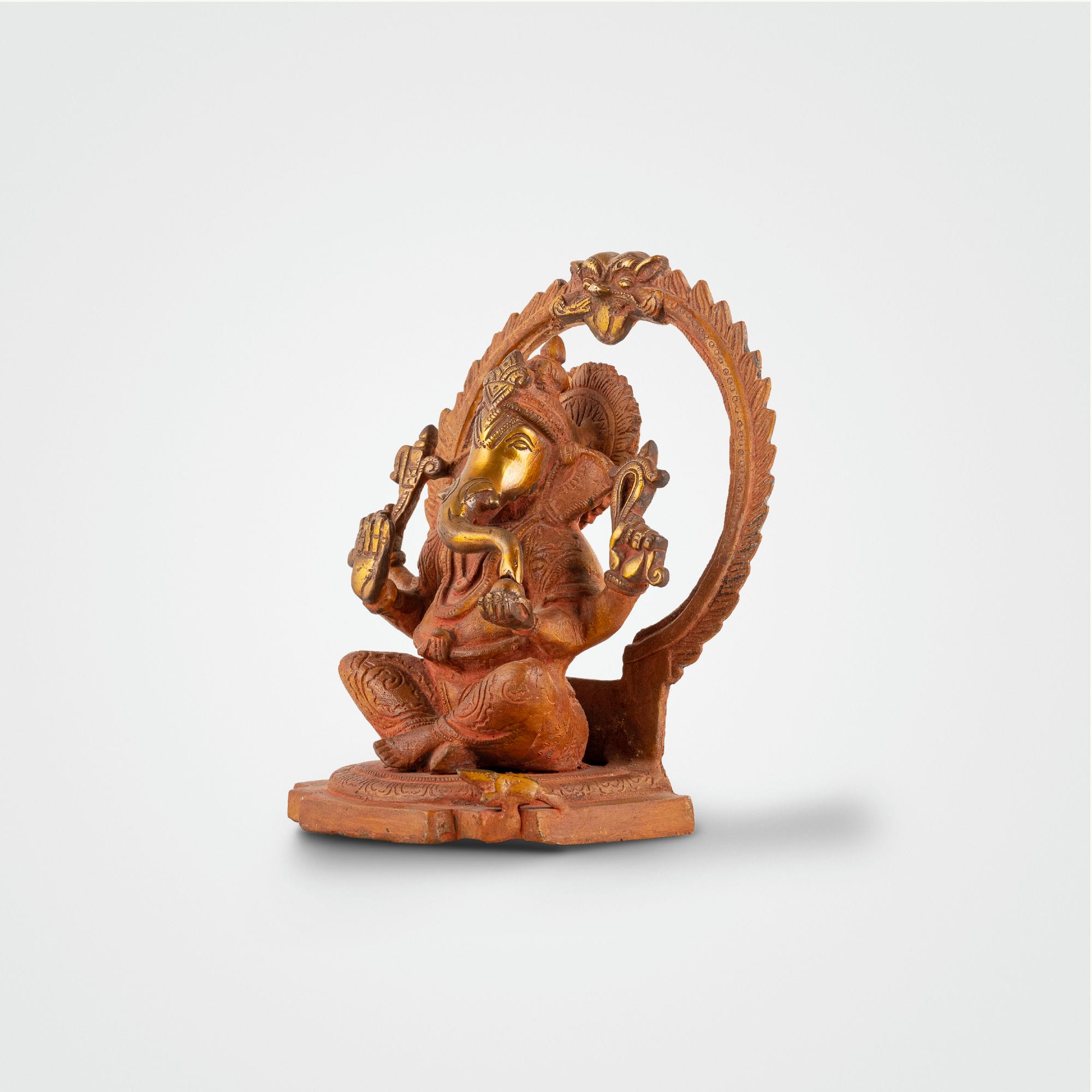 Red Oxidised Brass Ganesha Statue framed by a swirling halo on a home altar. 