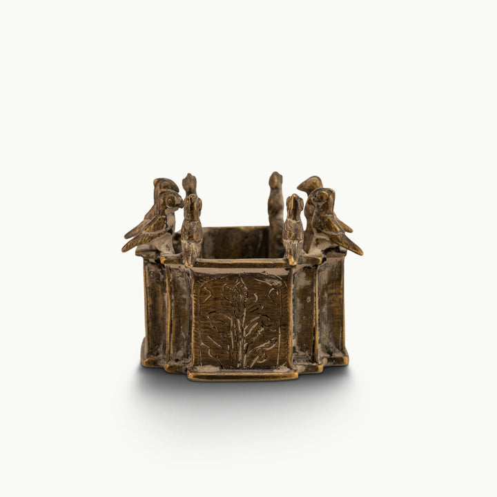 Engraved Brass Bird Vessel bordered by miniature avian sentinels on a study desk. 