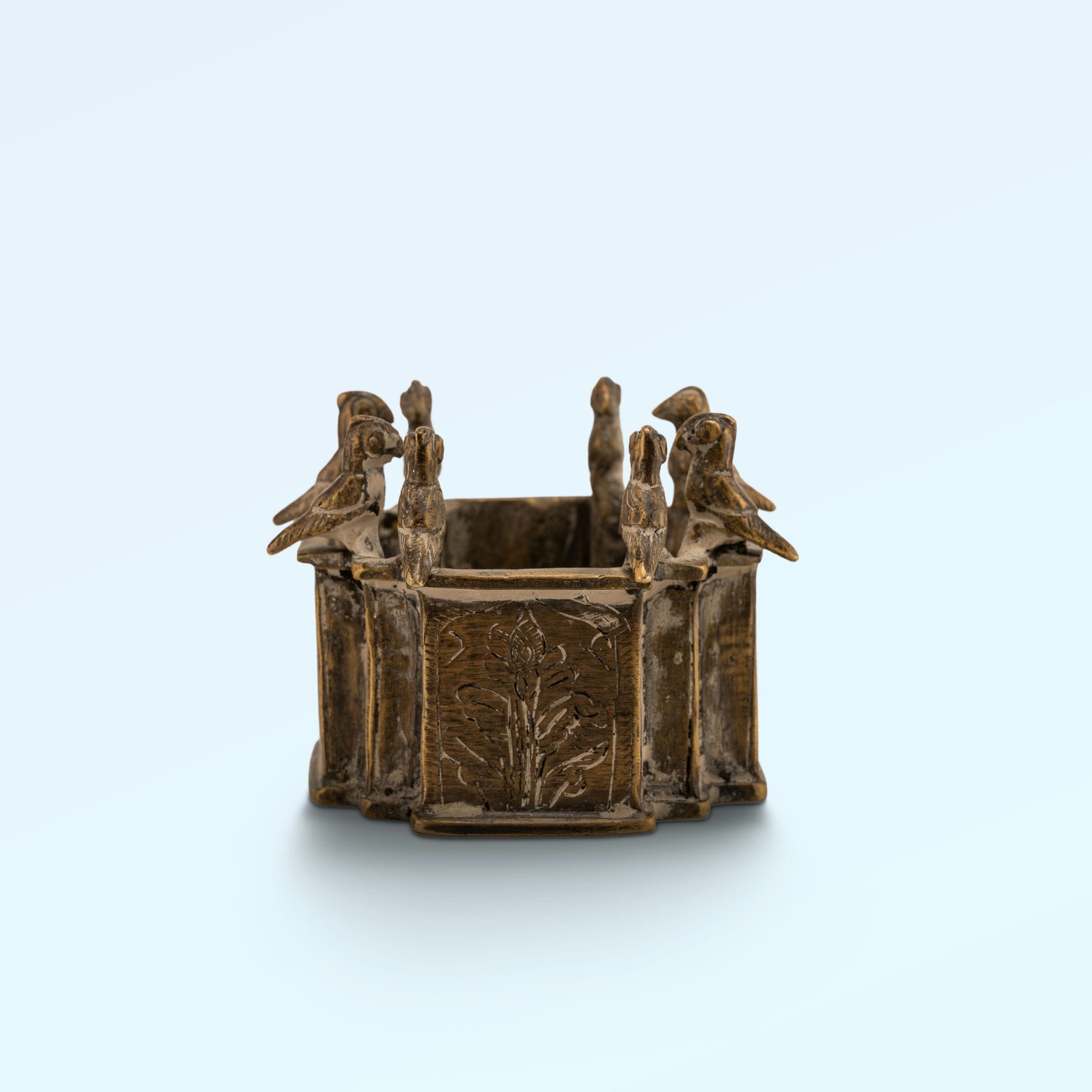 Engraved Brass Bird Vessel bordered by miniature avian sentinels on a study desk. 