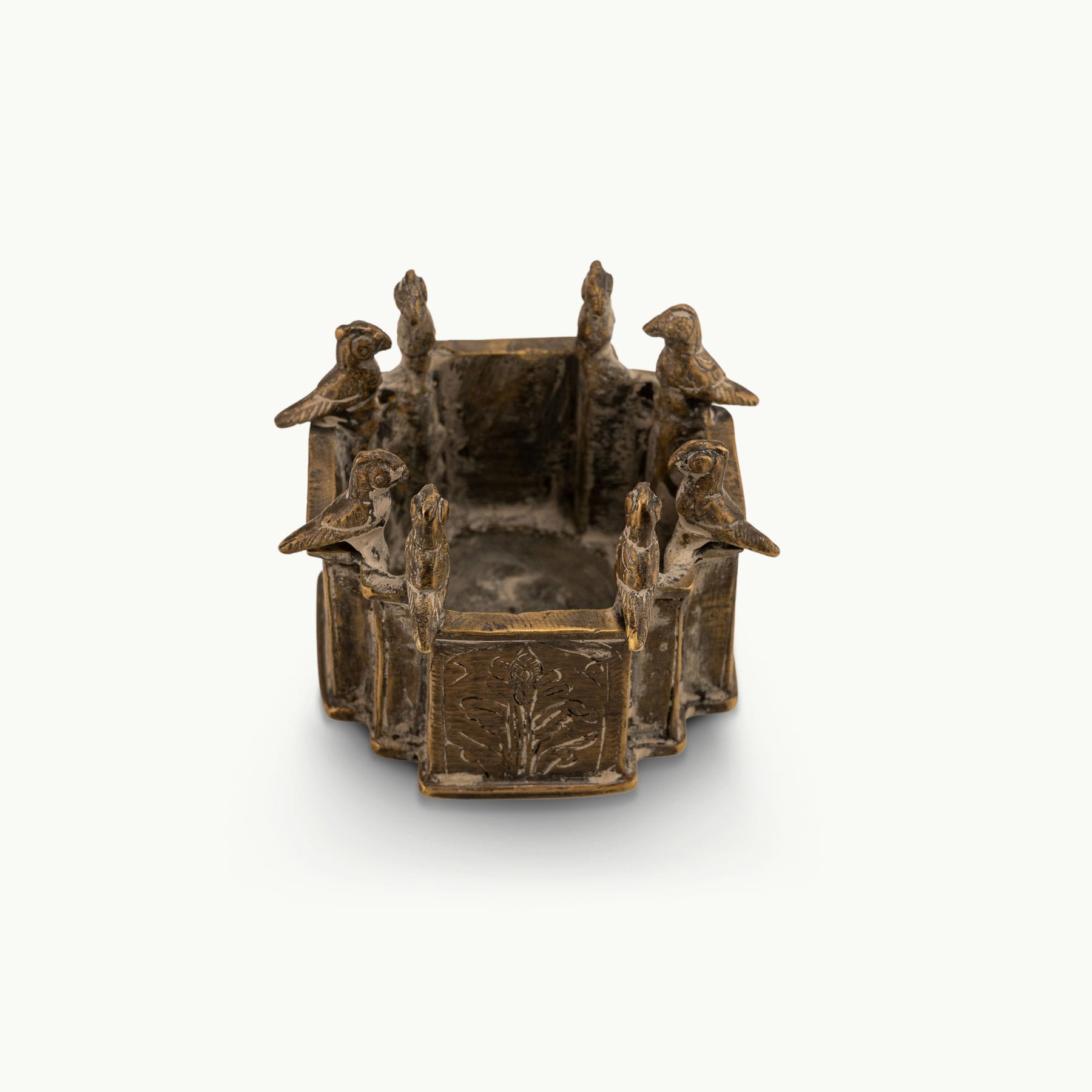 Engraved Brass Bird Vessel bordered by miniature avian sentinels on a study desk. 
