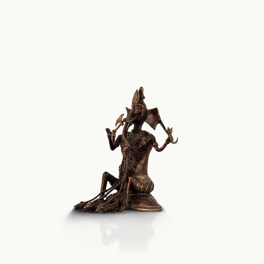 Dhokra Brass Ganesha Statue holding a tribal axe for a light-grained wooden console. 