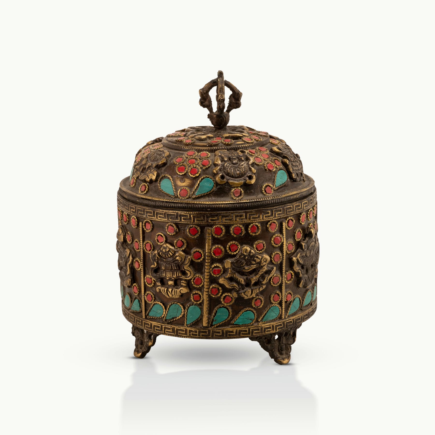 Stone Inlay Brass Vajra Box topped with a spiritual finial on an open bookshelf. 