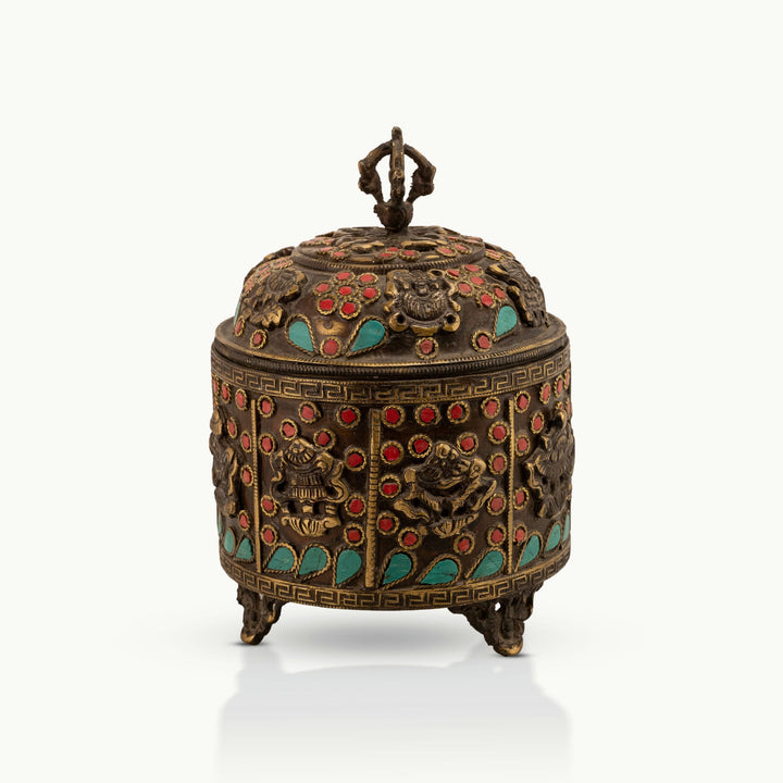 Stone Inlay Brass Vajra Box topped with a spiritual finial on an open bookshelf. 