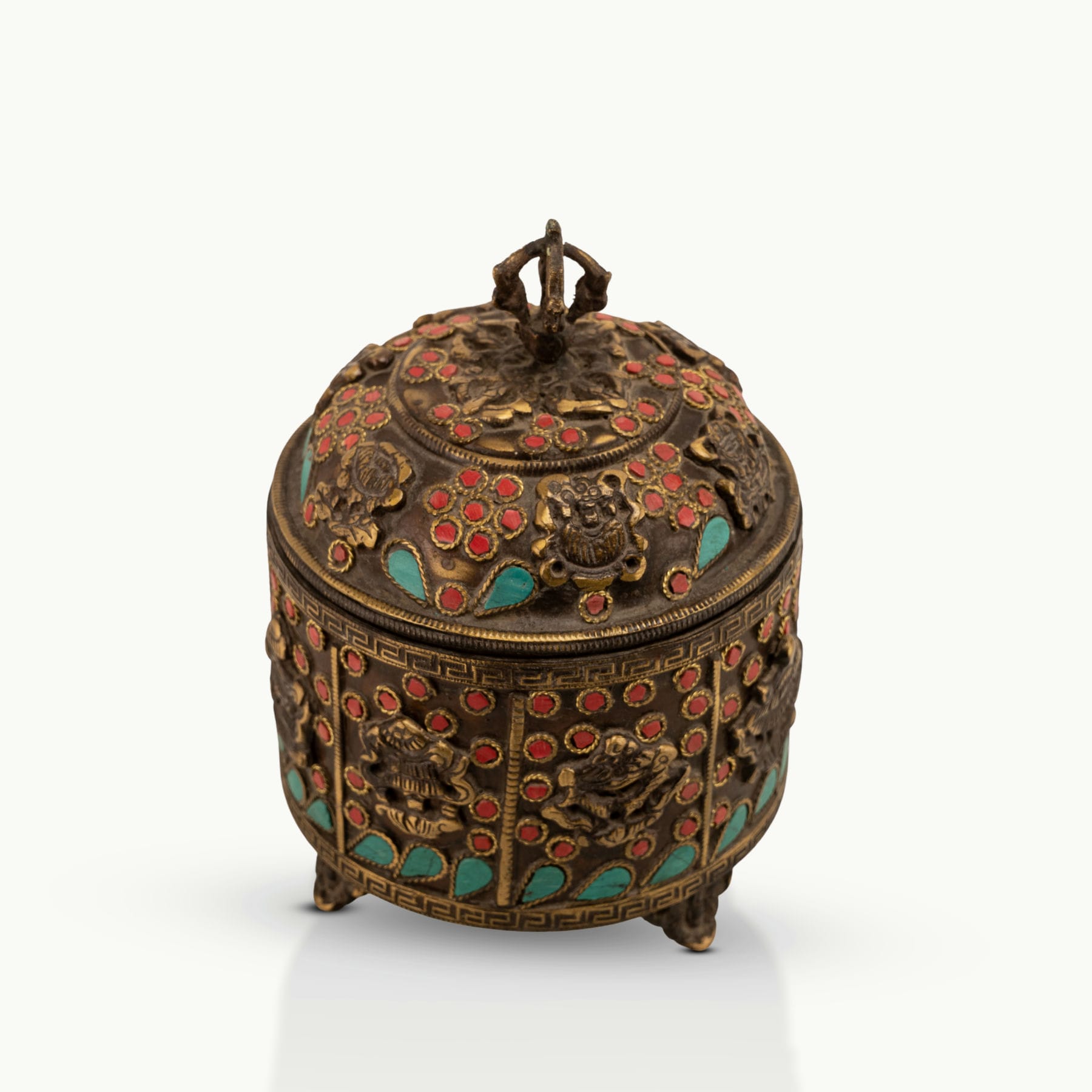 Stone Inlay Brass Vajra Box topped with a spiritual finial on an open bookshelf. 
