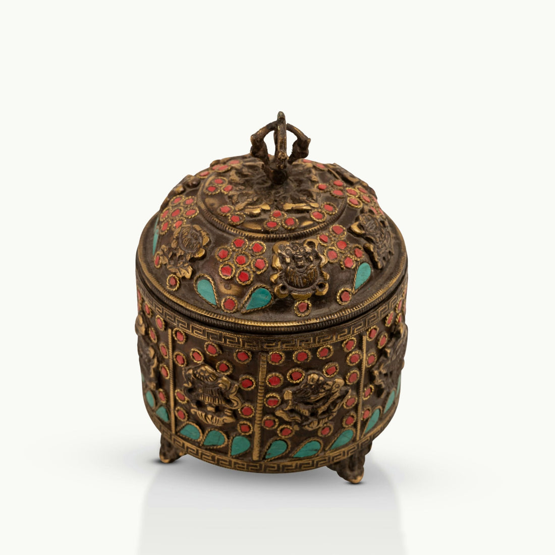 Stone Inlay Brass Vajra Box topped with a spiritual finial on an open bookshelf. 